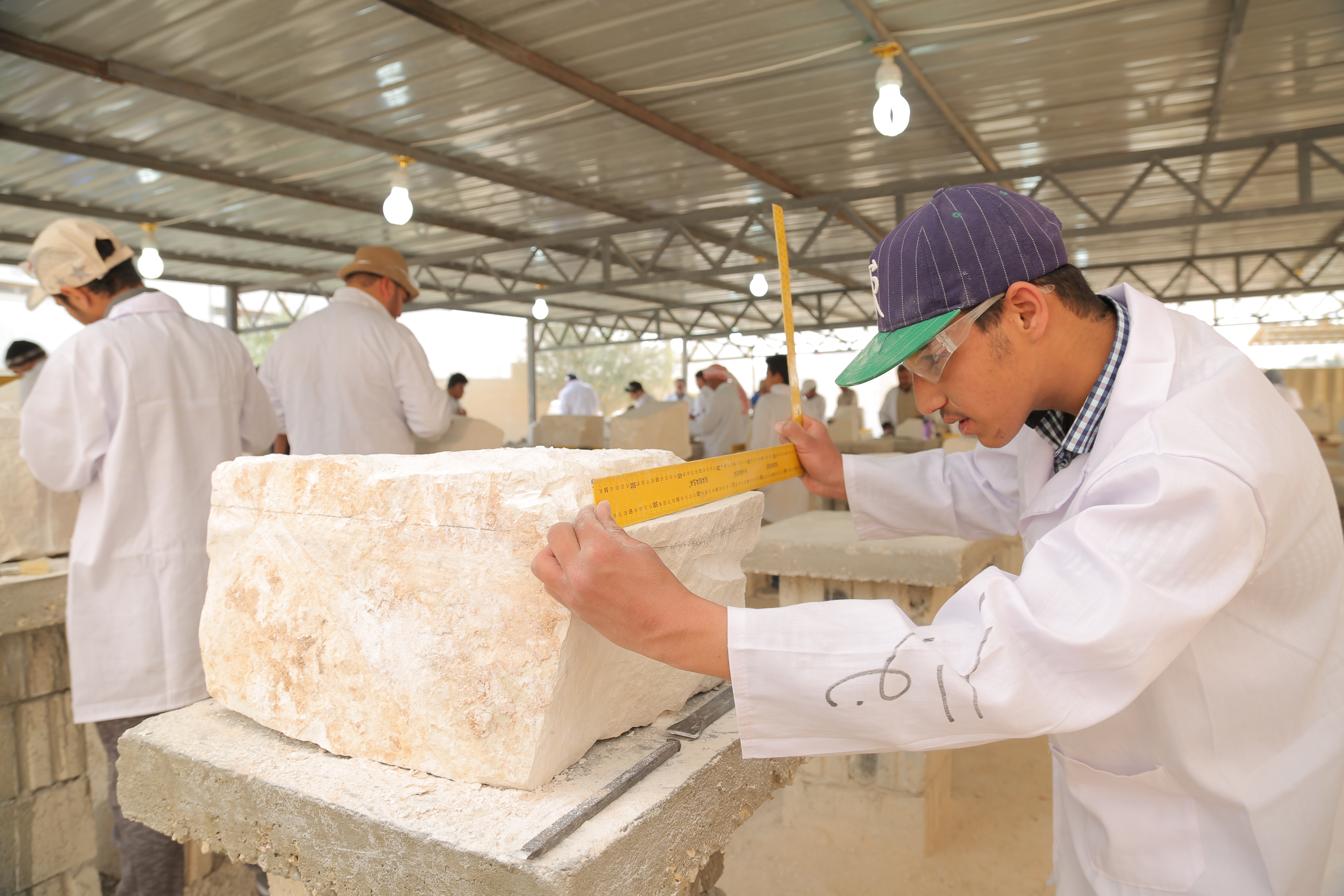 Nawar, a Syrian trainee, measures stone before carving