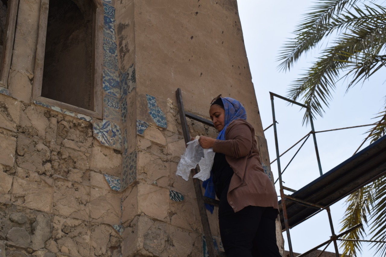 Abeer Saed Eledeen climbs a ladder to document the exterior of Takiyyat Ibrahim al-Gulshani.