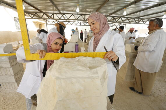 Ayat and Balqees, Jordanian trainees, measure a block of local stone