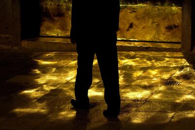 Silhouette of two legs amid street full of golden light