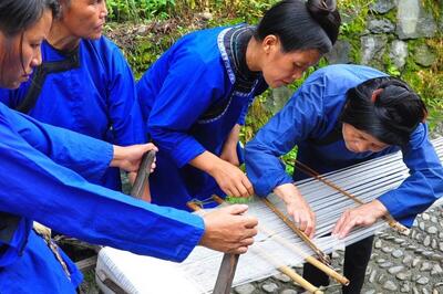Group of women in indigo clothing around a loom