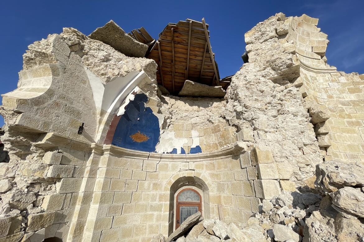 Partially collapsed white stone building with interior of dome painted blue