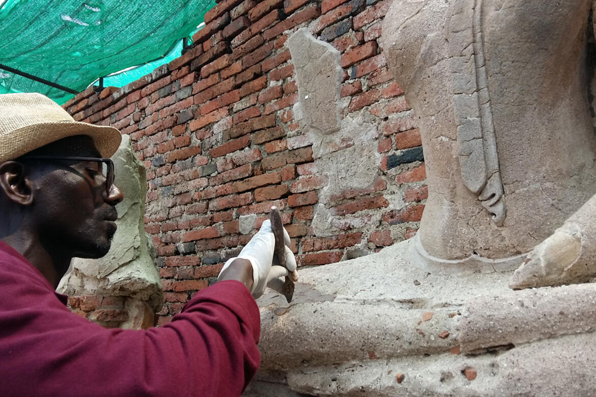 Ousmane Kounta working on stucco mortar for the Buddha statue