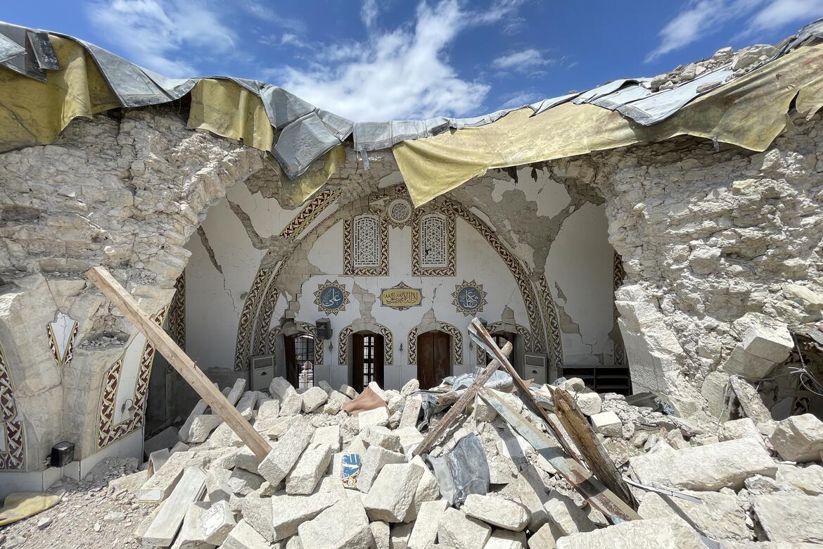 Rubble in foreground of religious building whose roof has collapsed after an earthquake