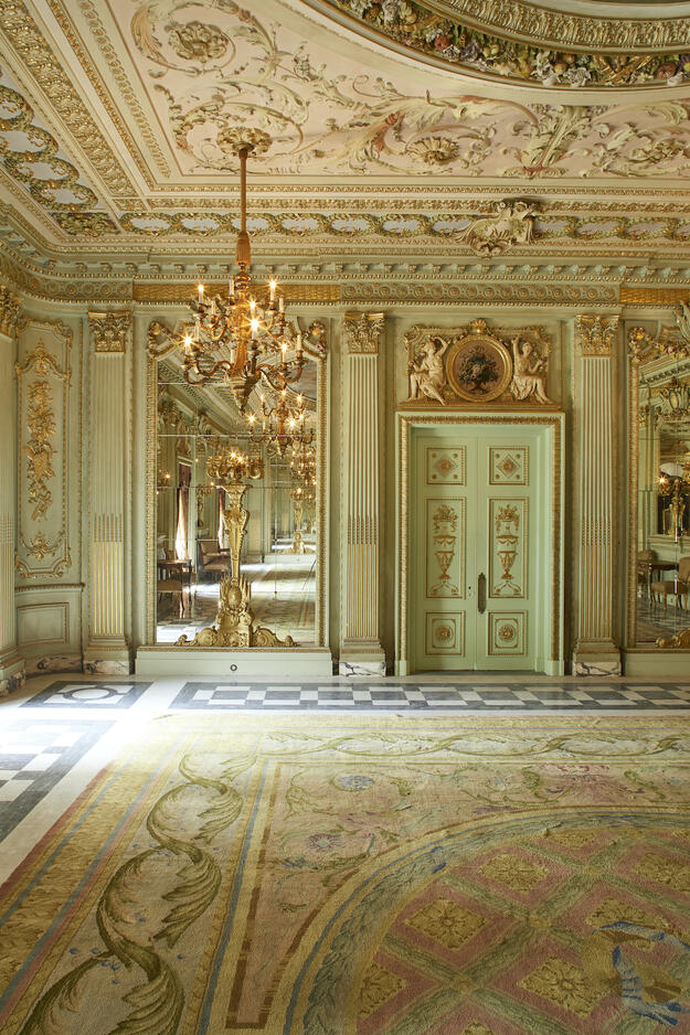 Opulent room inside palace with green walls and large mirrors