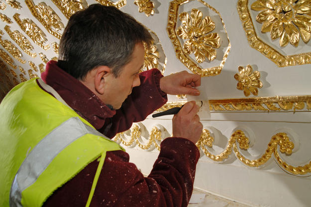 Conservator applying gilding to library ceiling, 2010