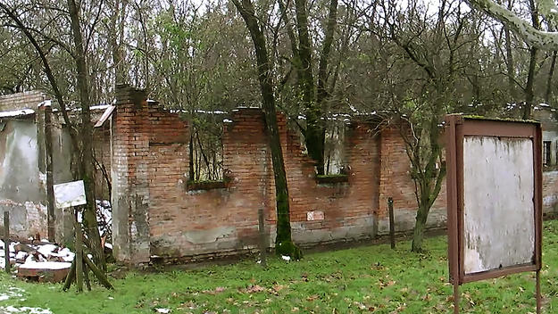 A building at the entrance to the Fossoli Concentration Camp is overrun with vegetation, 2012