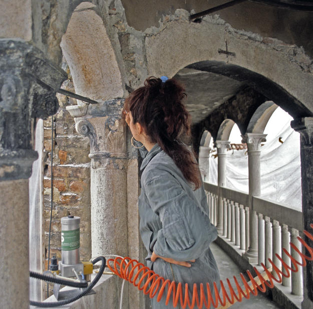 A conservator removes corrosive deposits that have blackened the column's capital, 1981