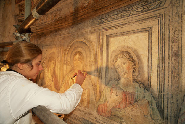 A conservator treating the lower registers of the frescoes on the wall of the circular cella, 1997