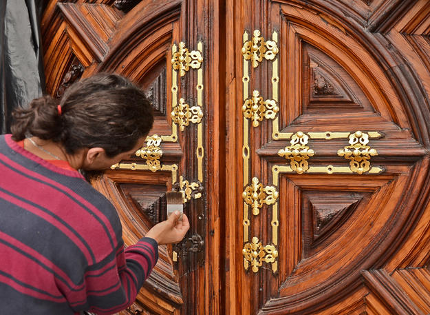 A conservator applies gold leaf to a door, 2013