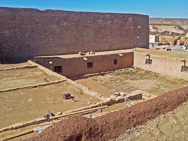 A view of the courtyard and convento shows the earthen roof and its stone parapets, 2014