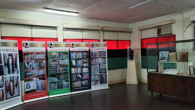 White-walled room with red, black, and green cloth over windows and informational displays along the walls.