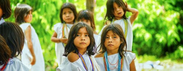 Group of children in white clothing with colorful bead necklaces