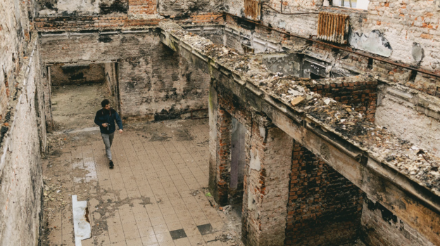 Man walking through remains of bombed building, seen from above