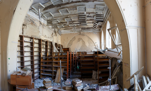 Debris-strewn room with broken bookshelves and damaged ceiling