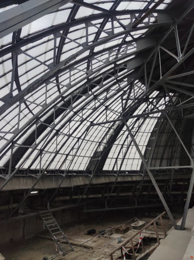 Inside of dome with steel girders and glass showing gray sky outside