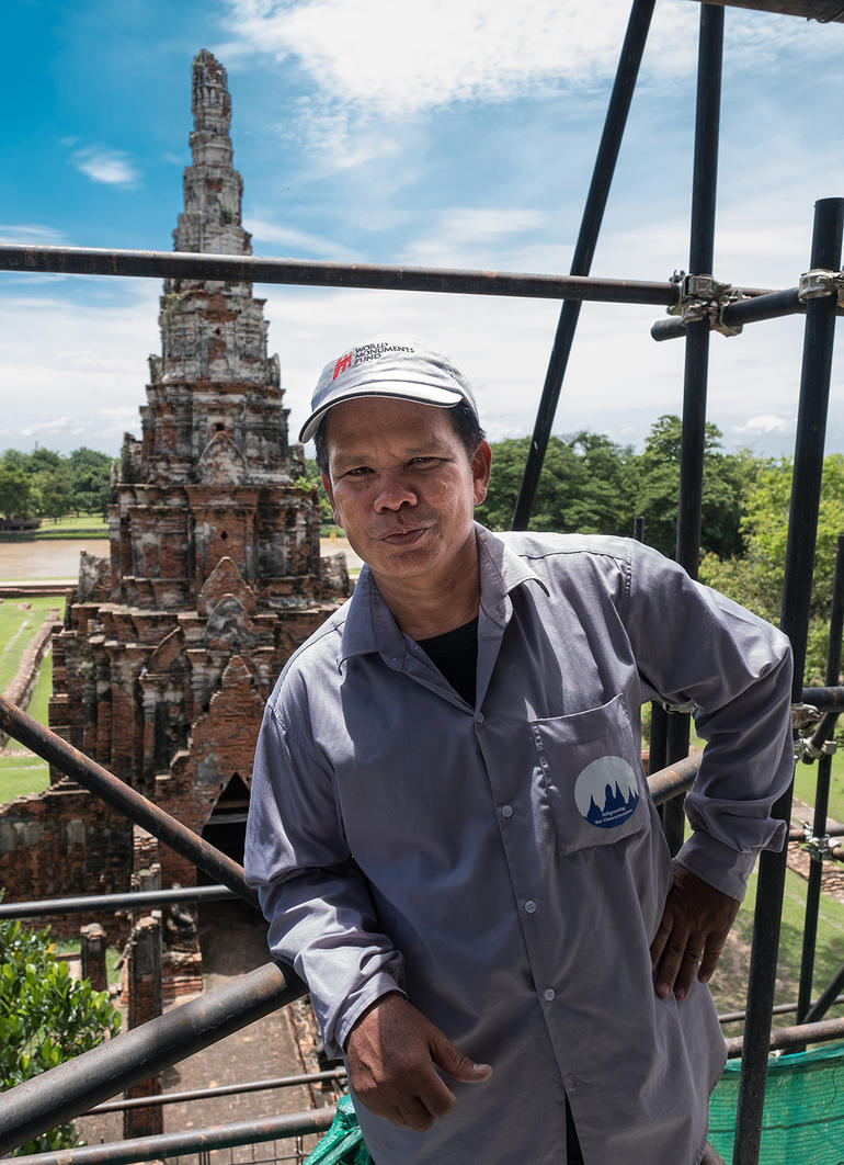 Conservator Khun Kee poses on scaffolding at Wat Chaiwatthanaram.