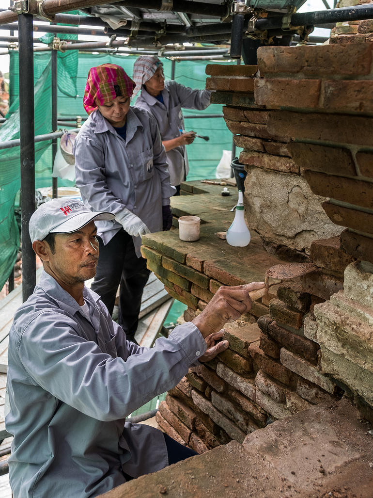 Khun Nu, Khun Peng, and Khun Mali on Meru C3 performing masonry conservation techniques.